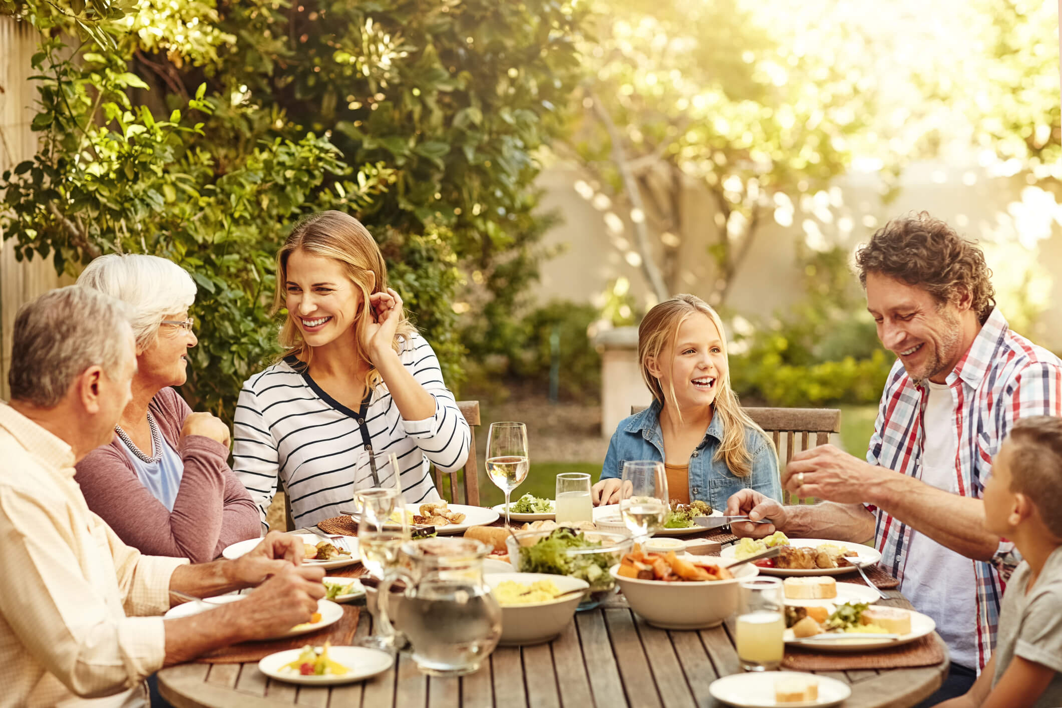 Multi-generational family having dinner outside on a sunny day