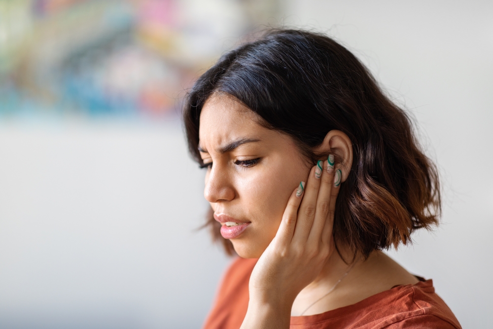 Lady holding her ear due to tinnitus.